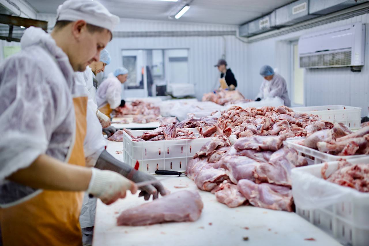 Сотрудники за разделкой мяса в цехе